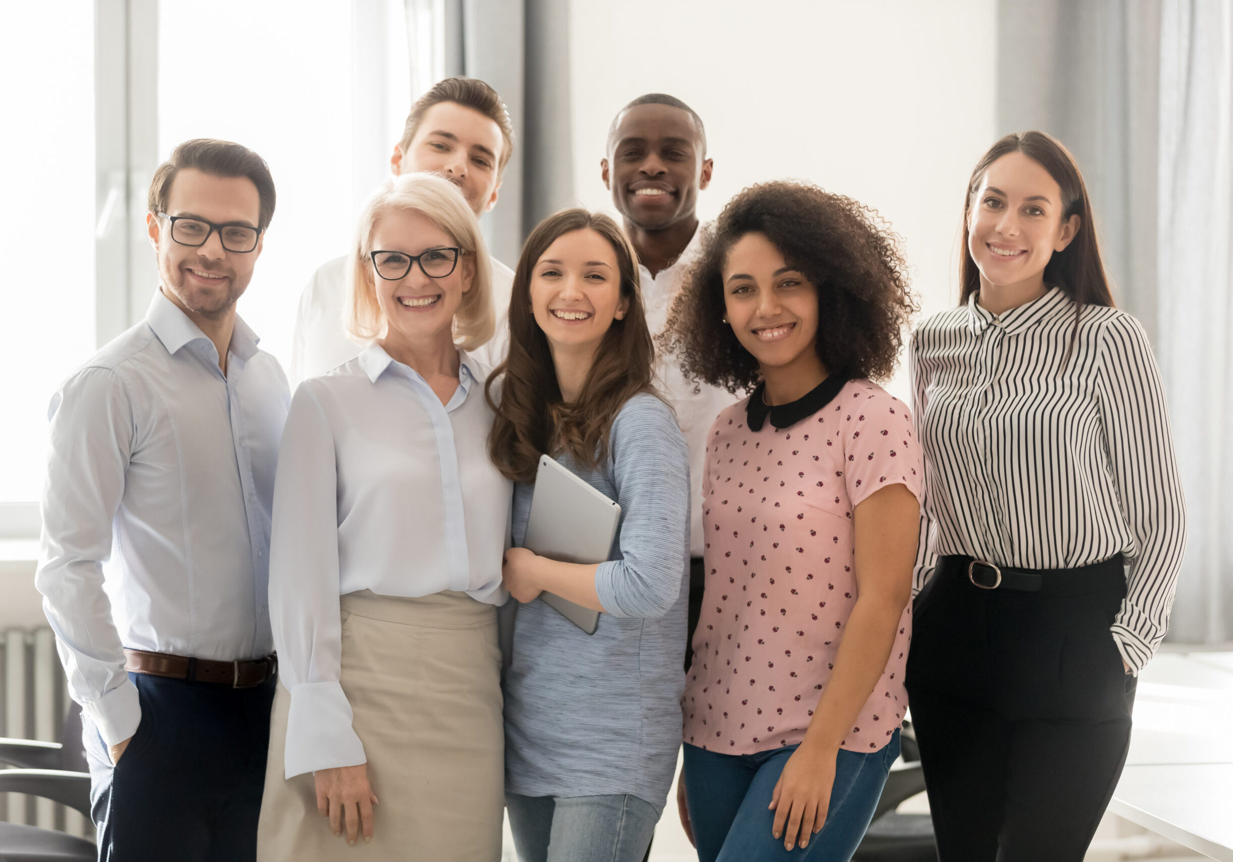 Happy multicultural work team employees group looking at camera posing in office, smiling multi-ethnic company staff workers, workforce members, business people managers standing together, portrait